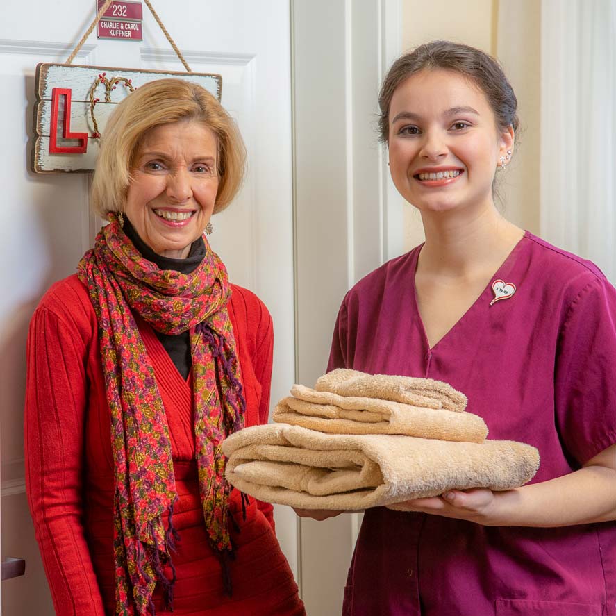 A team member delivering fresh linens to a resident at Pioneer Ridge